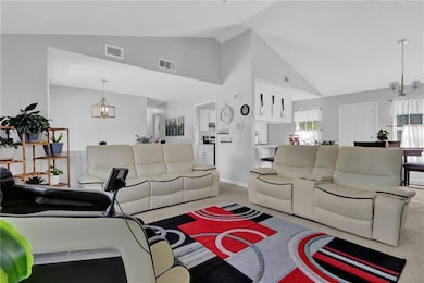 Carpeted living area featuring a chandelier and high vaulted ceiling