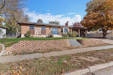 Single story home featuring a chimney, solar panels, an attached garage, and brick siding
