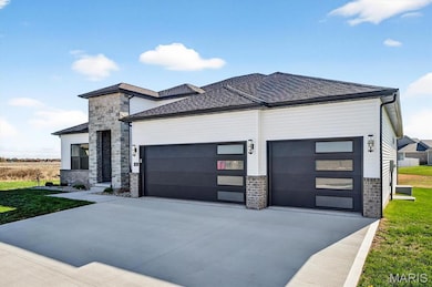 View of front of property with concrete driveway, a front yard, and a garage