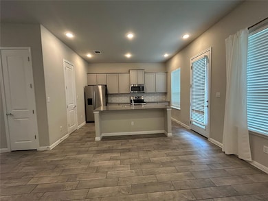 Kitchen with stainless steel appliances, wood fin
