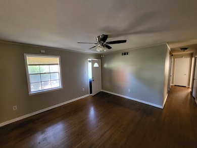 Empty room with dark hardwood / wood-style flooring, ceiling fan, and crown molding