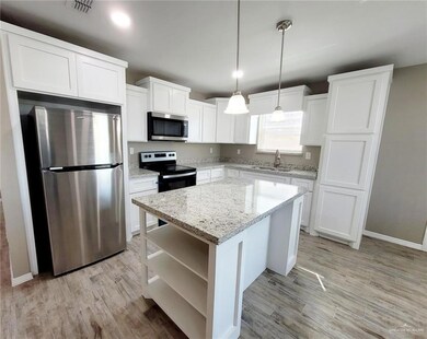 Kitchen with stainless steel appliances, open shelves, white cabinets, light wood-style floors, and a center island