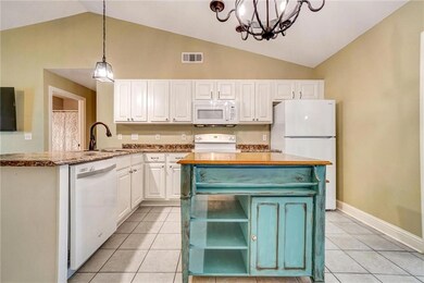 Kitchen with white appliances, lofted ceiling, white cabinets, a chandelier, and light tile patterned flooring