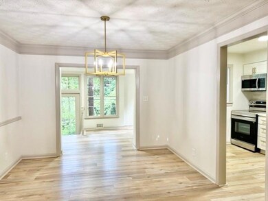 Unfurnished dining area with light wood-type flooring, a textured ceiling, and ornamental molding