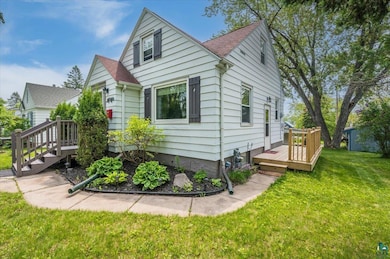 View of front facade featuring a wooden deck, a front lawn, and roof with shingles