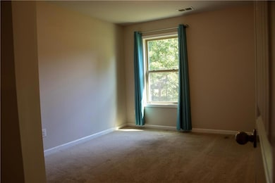 Spare room featuring carpet flooring and baseboards