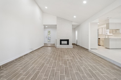 Unfurnished living room with recessed lighting, wood tiled floors, a fireplace, and high vaulted ceiling