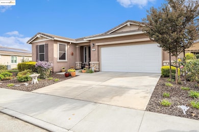 Ranch-style house featuring a tiled roof, concrete driveway, stucco siding, and a garage