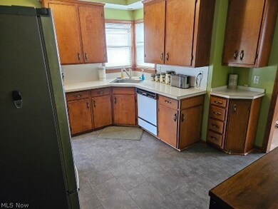 Kitchen with white dishwasher, sink, tile floors, and fridge