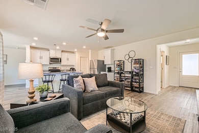 Living room with a ceiling fan, light wood-style floors, and recessed lighting