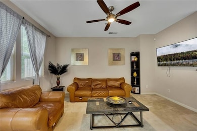 Living area with ceiling fan and light colored carpet