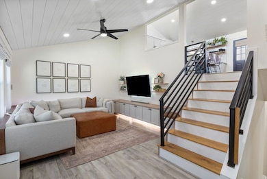 Living area featuring plenty of natural light, light wood-style flooring, recessed lighting, lofted ceiling, and stairway
