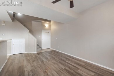 Unfurnished living room with wood finished floors, ceiling fan, and stairs