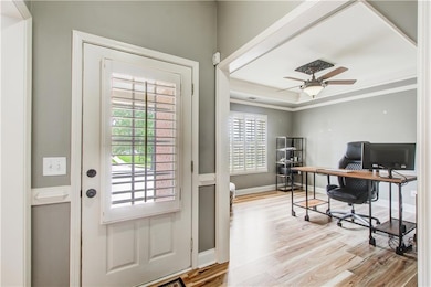 Office area with light wood-style flooring, a ceiling fan, and crown molding