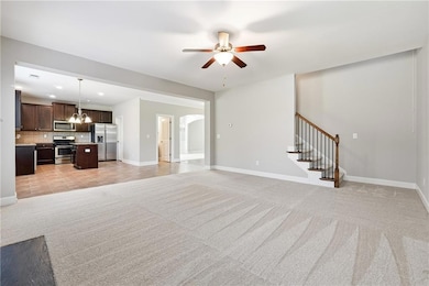 Unfurnished living room with light carpet, a chandelier, ceiling fan, stairway, and recessed lighting
