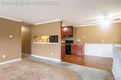 Kitchen with crown molding, black appliances, wainscoting, a ceiling fan, and light wood finished floors