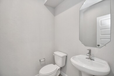 This half bathroom features a stylish pedestal sink, modern hardware, and bright recessed lighting, creating a sleek and inviting space. Sample photo of completed home with similar floor plan. Actual colors and selections may vary.
