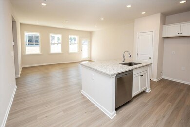 Kitchen with stainless steel dishwasher, a sink, light wood-style floors, white cabinets, and recessed lighting
