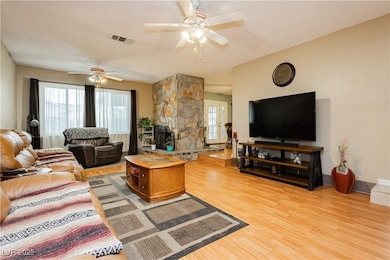 Living room featuring ceiling fan and light wood-s