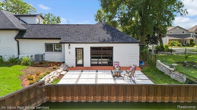 Rear view of property featuring stucco siding, stone siding, a patio, and a shingled roof