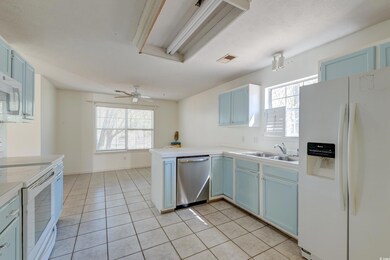 Kitchen with blue cabinetry, white appliances, a s
