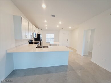 Kitchen featuring kitchen peninsula, sink, white cabinets, and appliances with stainless steel finishes