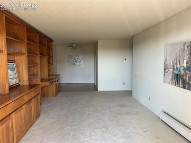 Unfurnished living room featuring a baseboard heating unit, light colored carpet, a textured ceiling, and ceiling fan