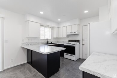 Kitchen with light countertops, a peninsula, white appliances, white cabinetry, and recessed lighting