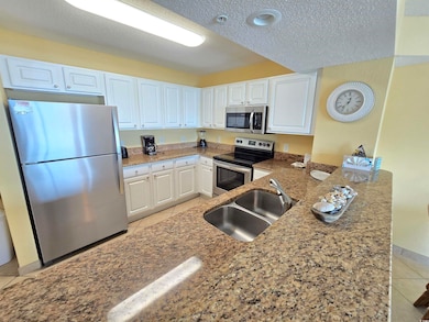 Kitchen featuring a sink, white cabinets, light ti