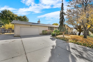 View of front of property featuring brick siding, concrete driveway, an attached garage, and a chimney