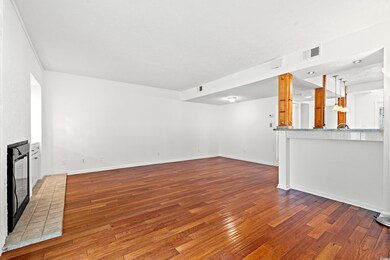 Unfurnished living room featuring wood-type flooring and a brick fireplace