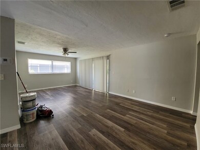 Empty room with ceiling fan, dark hardwood / wood-style flooring, and a textured ceiling