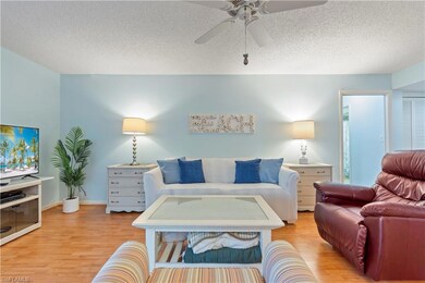 Living room with light wood finished floors, ceiling fan, and a textured ceiling
