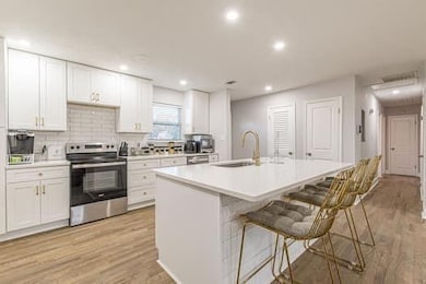 Kitchen featuring stainless steel appliances, white cabinets, light wood-style flooring, light countertops, and recessed lighting