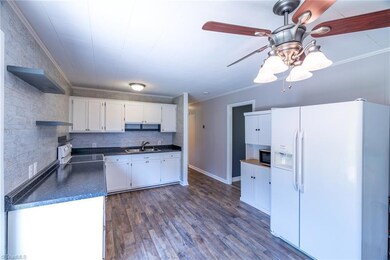 Kitchen and Dining Area: Features include new LVP flooring for easy cleaning, the patio door to the rear deck and backyard, lots of natural lighting with the patio door and windows, a ceiling fan with light, decorative crown molding, bright cabinets and decorative crown molding and the decorative backsplash for easy cleaning. You have a stove and refrigerator that will both convey at closing. The hallway leads to the bedrooms and bathroom.