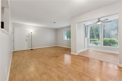 Unfurnished living room featuring light wood-type flooring, a textured ceiling, and a ceiling fan