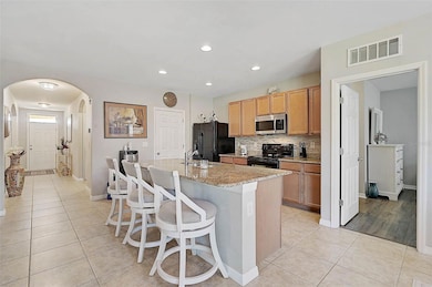 The granite island offers ample space for meal prep, dining, and entertaining, serving as the stunning centerpiece of the kitchen.