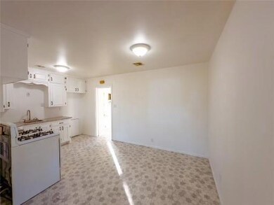 Kitchen featuring white cabinetry, sink, stove, and light colored carpet