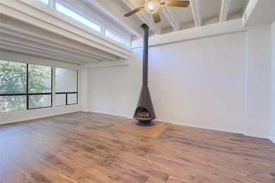 Unfurnished room with a wood stove, beam ceiling,