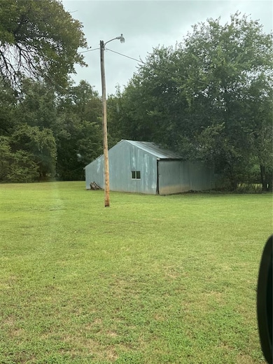 View of grassy yard with a pole building and an outdoor structure
