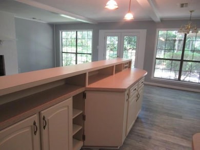 Kitchen with open shelves, dark wood-style floors, white cabinetry, hanging light fixtures, and healthy amount of natural light