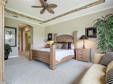 Carpeted bedroom featuring arched walkways, basebo