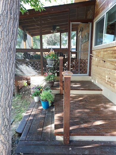 Wooden terrace featuring ceiling fan and a sunroom