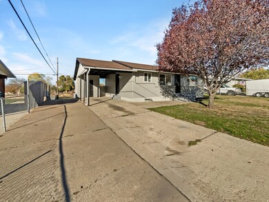 Rear view of property with a lawn, driveway, and roof with shingles