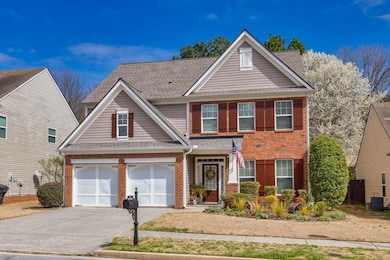 Traditional-style house featuring brick siding, driveway, a shingled roof, cooling unit, and a garage