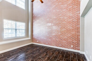 Empty room with brick wall, ceiling fan, dark hard