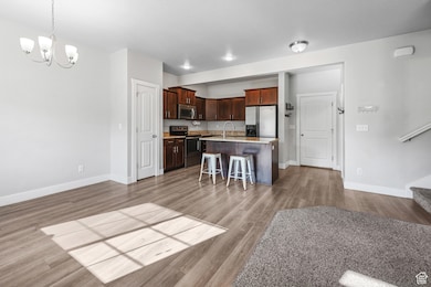 Kitchen with a kitchen breakfast bar, stainless steel appliances, a kitchen island with sink, a chandelier, and decorative light fixtures