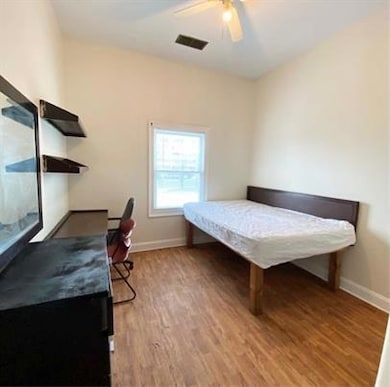 Bedroom with light wood-style floors, an office area, and a ceiling fan