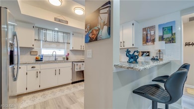  Granite counters, white cabinets, appliances with stainless steel finishes, light wood-style floors, and a kitchen bar