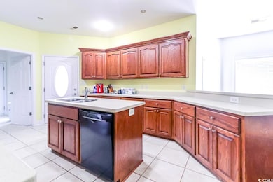 Kitchen with dishwasher, a sink, light tile patterned flooring, and a center island with sink